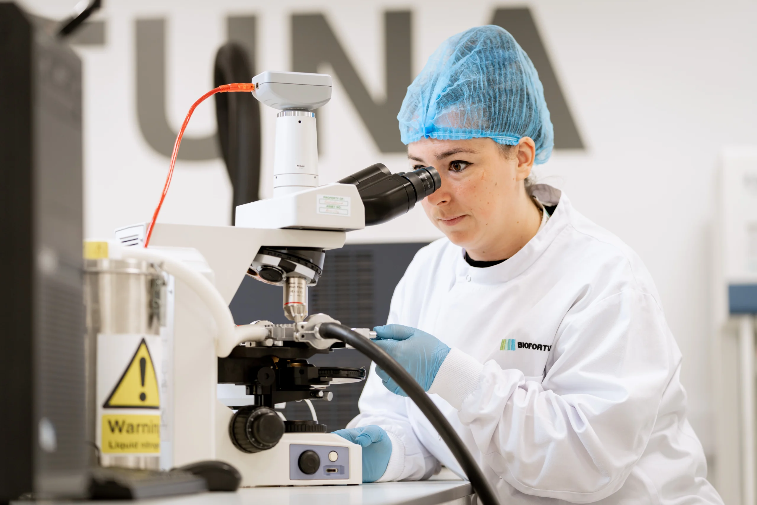 Biofortuna colleague in PPE, utilising a microscope
