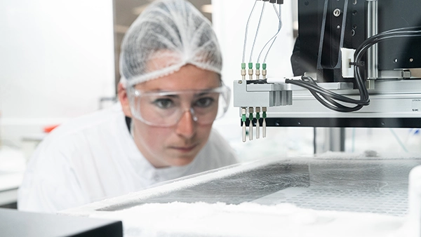 Assay development: a female colleague focused on machinery to ensure it is correctly producing the assay as required